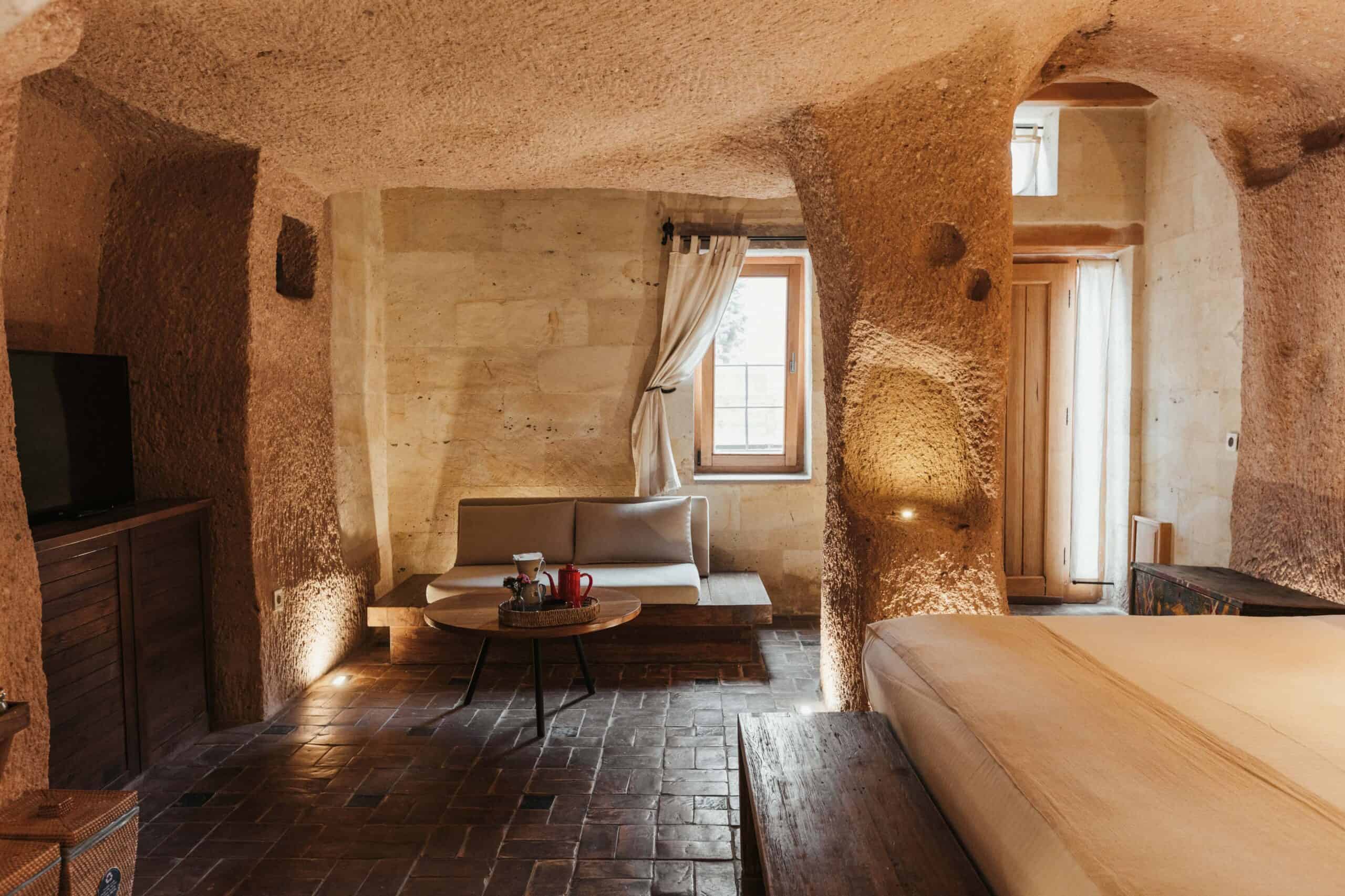 Junior Suite: cave room with bed, stone walls and arched window