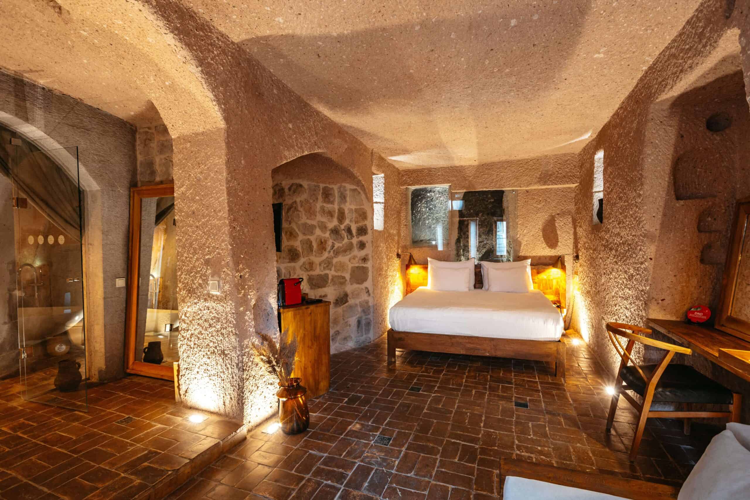 Junior Suite: long cave room with double bed and carved stone walls