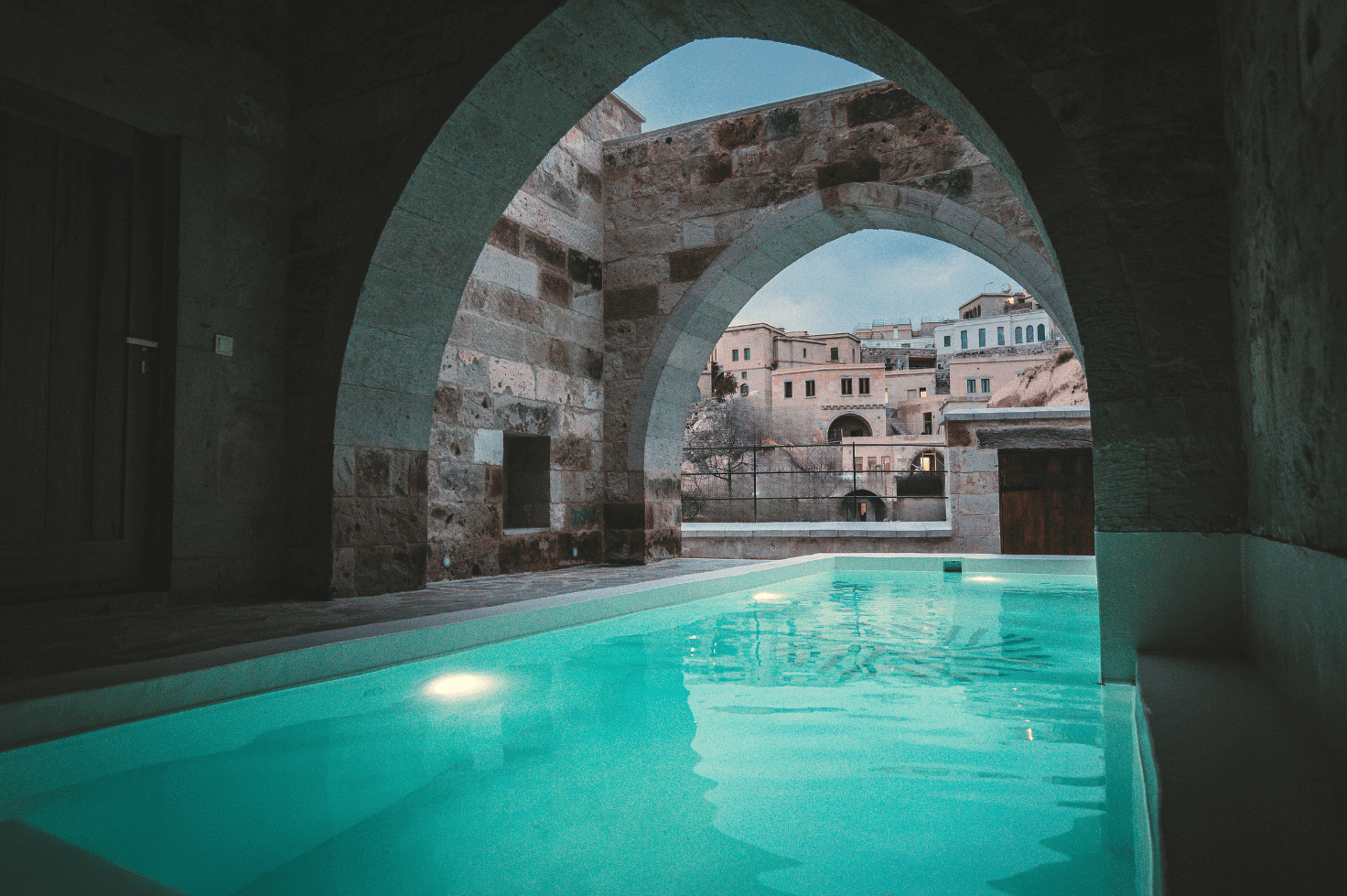 Semi-Open Pool Suite: pool under a stone arch opening onto the village