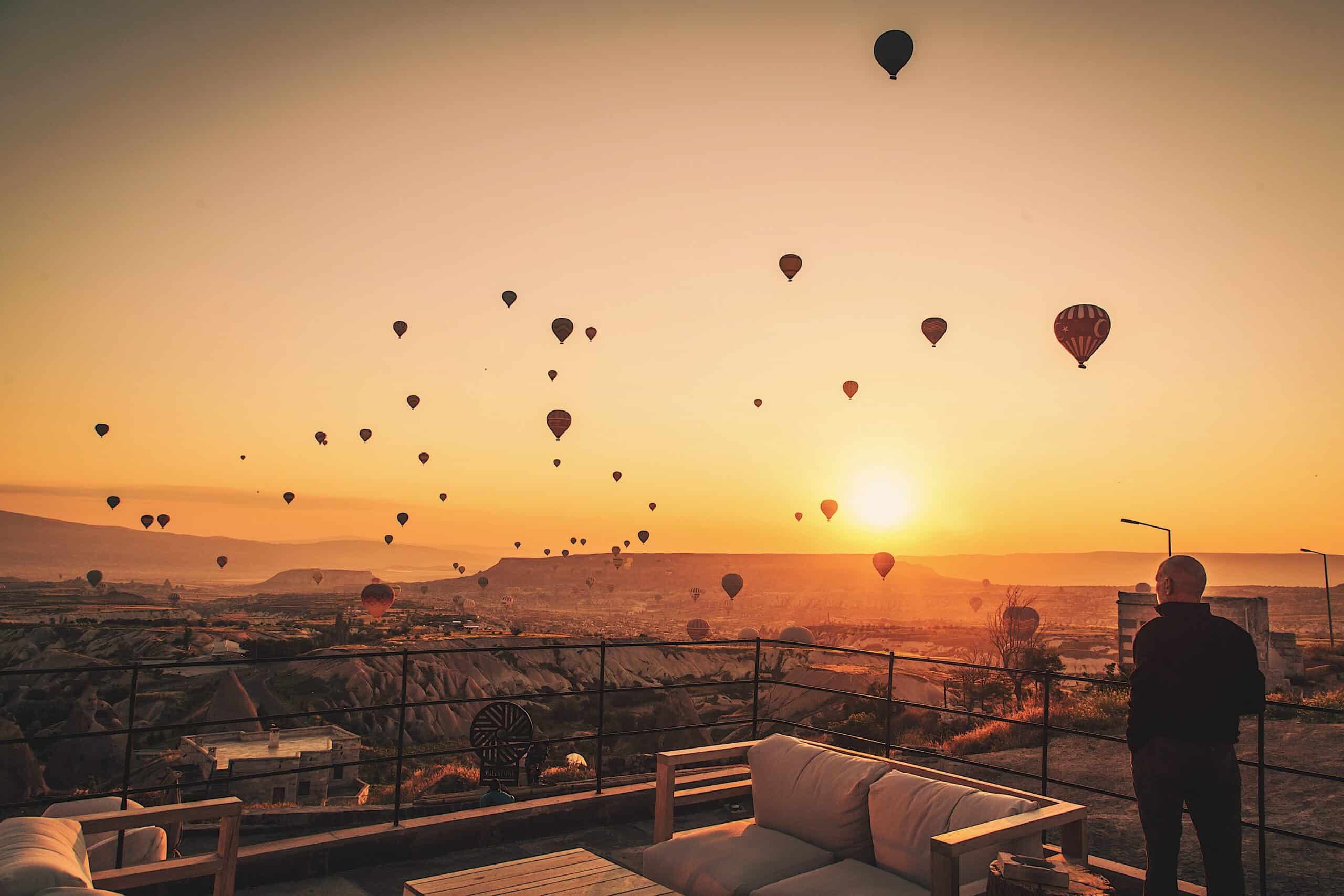 Guest watching hot air balloons at sunrise from the hotel terrace