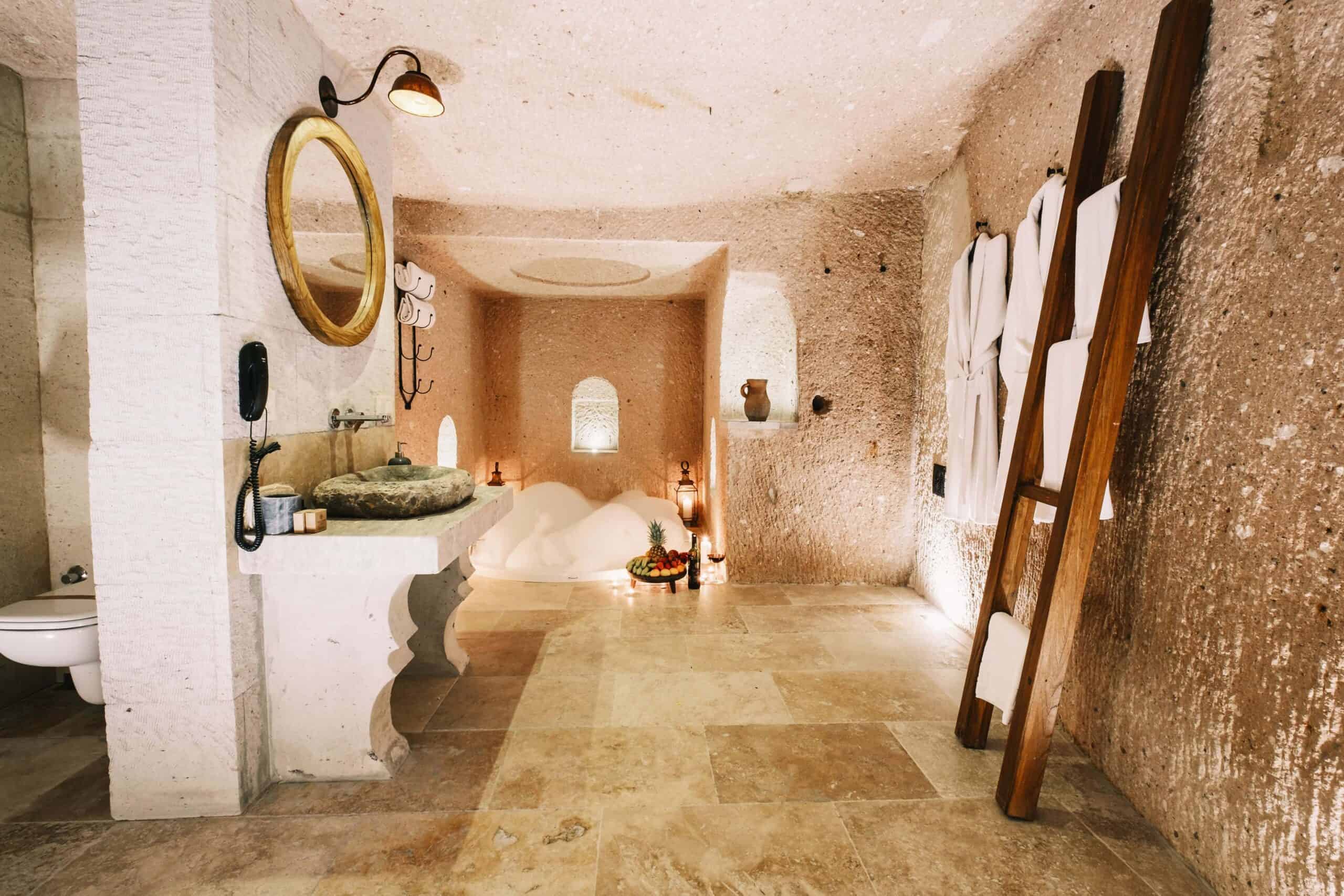 Suite: cave bathroom with stone sink and ladder towel rack