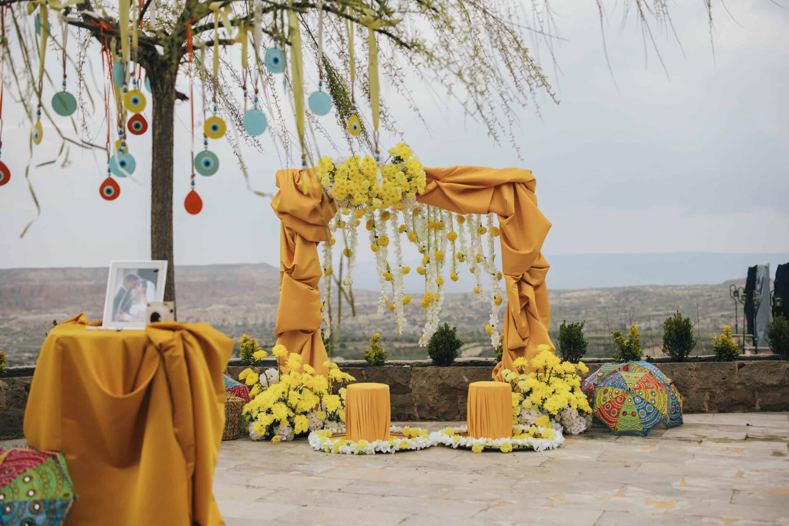Outdoor event setup with a yellow floral arch and decorated tree