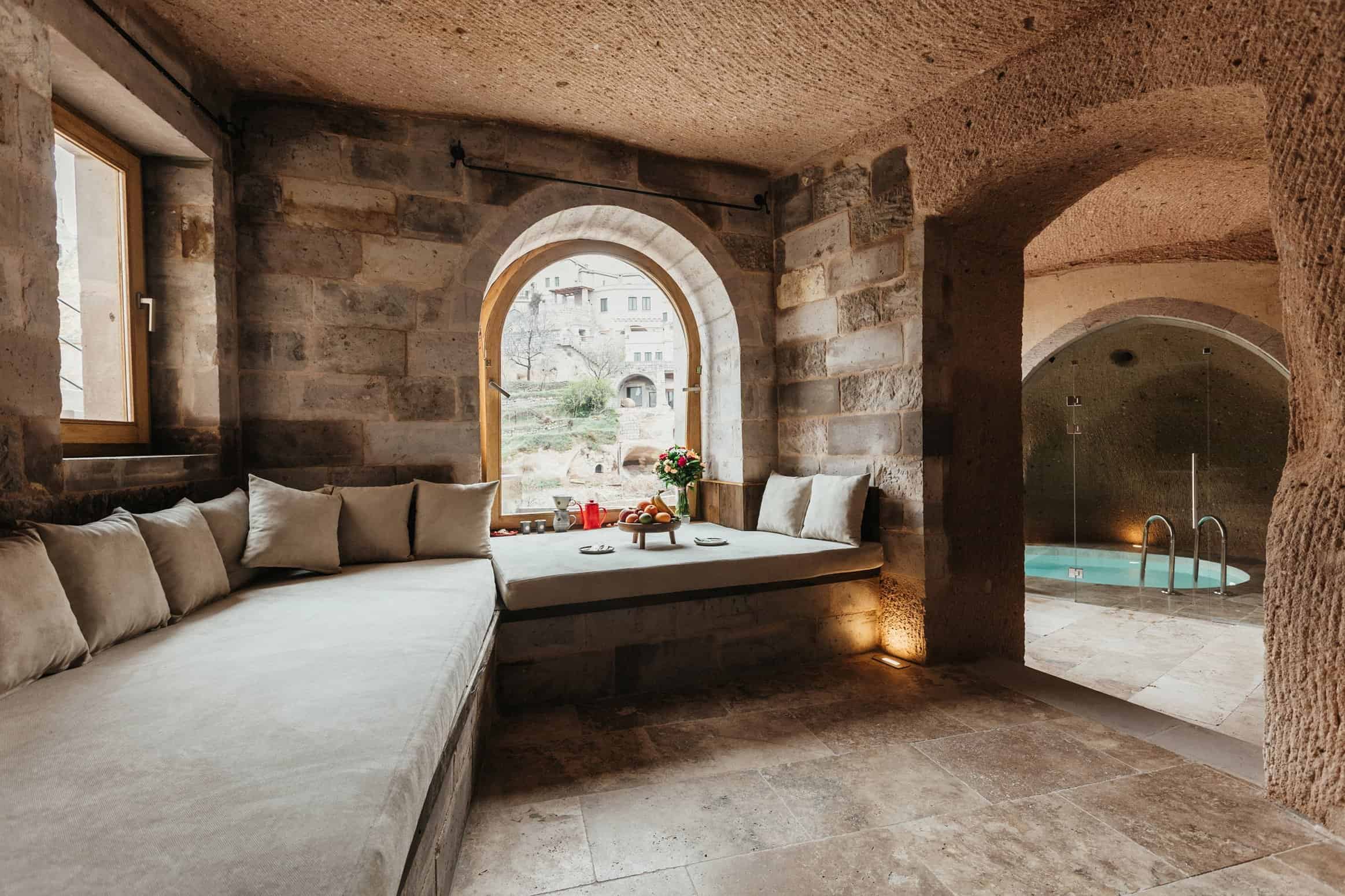 Grand Cave Pool Suite: sitting area with arched window and view of the indoor pool