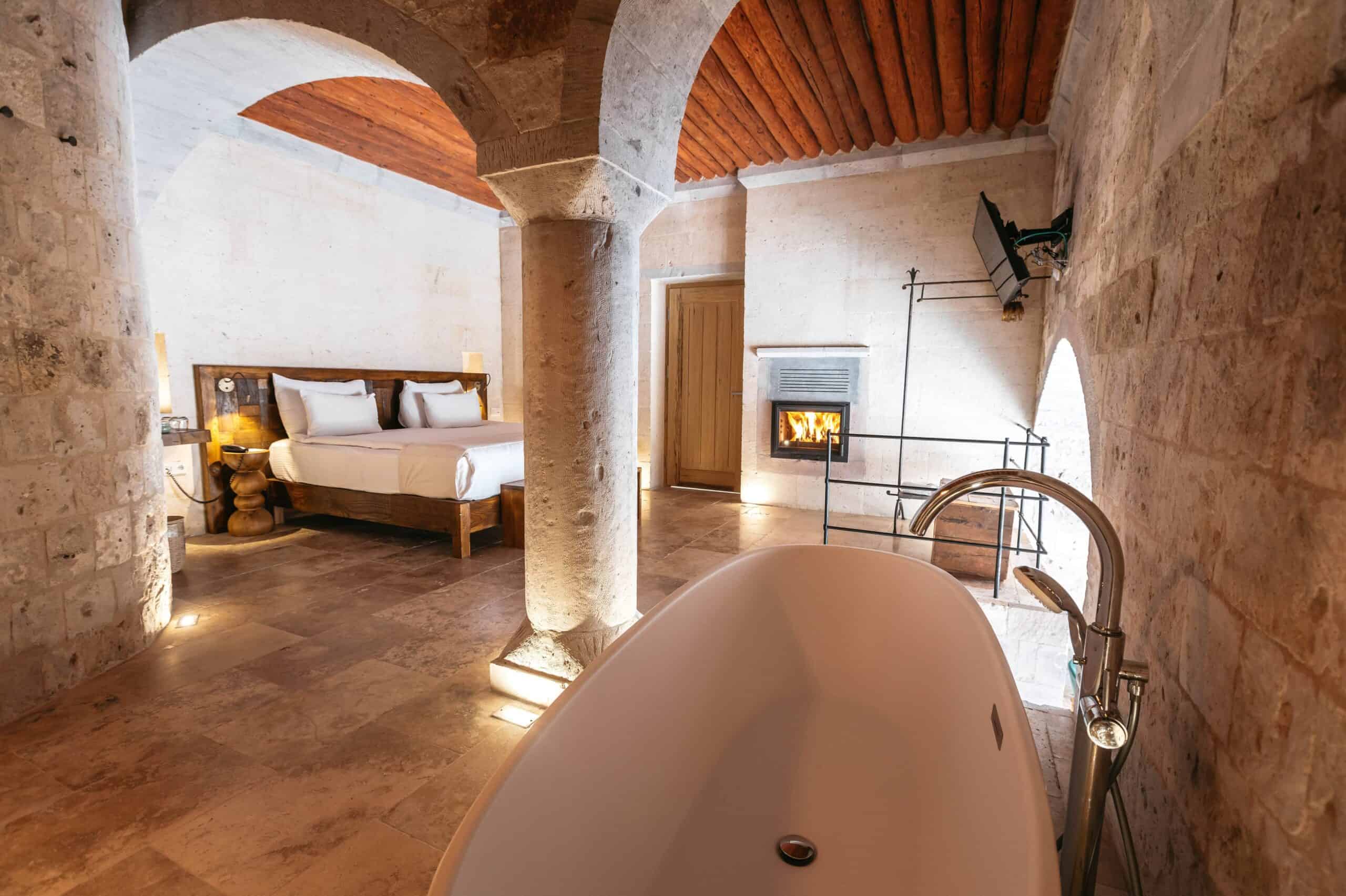 Semi-Open Pool Suite: freestanding bathtub with a view of the bedroom and fireplace