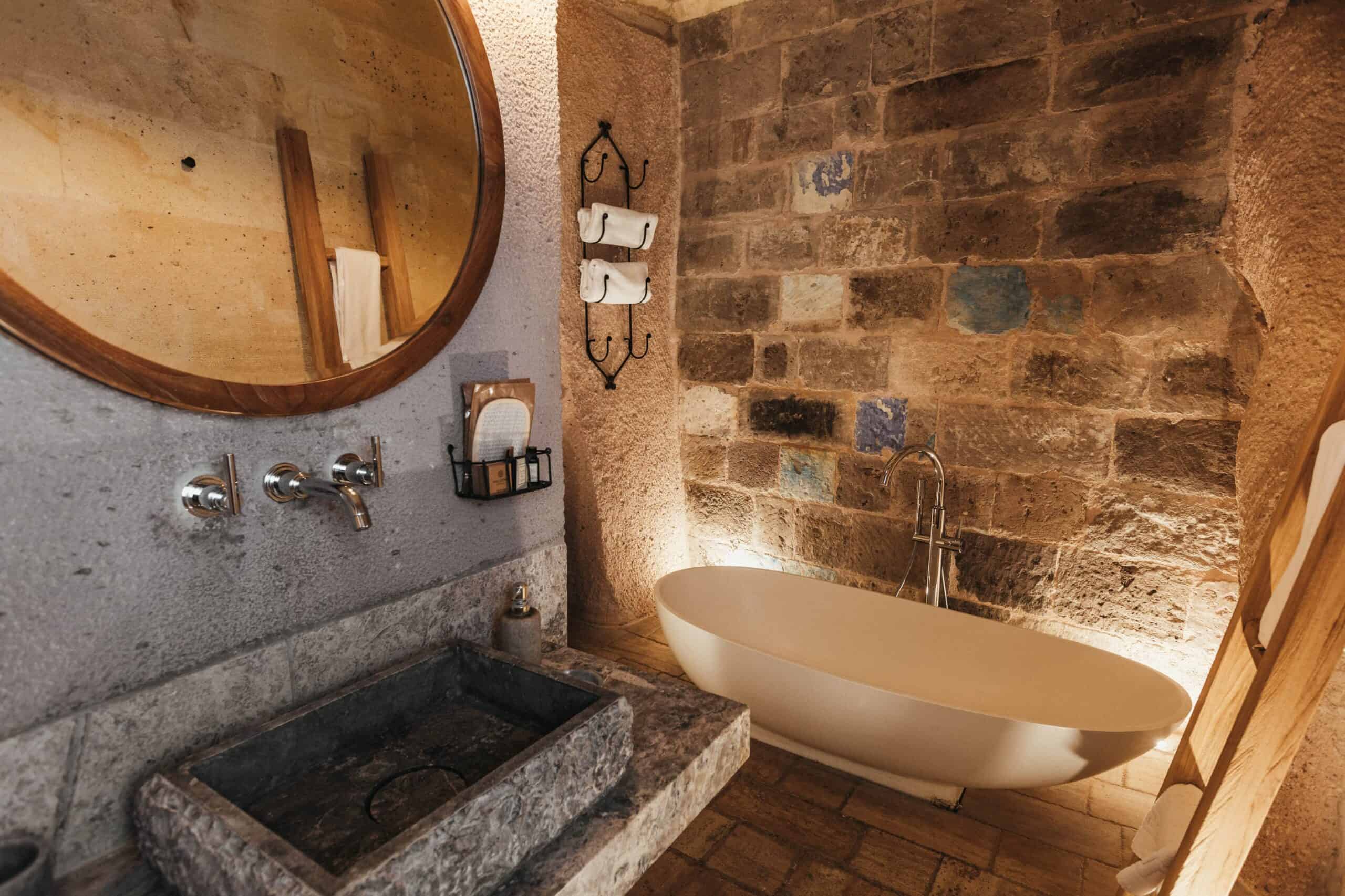 Junior Suite with View: stone bathroom with bathtub and round mirror