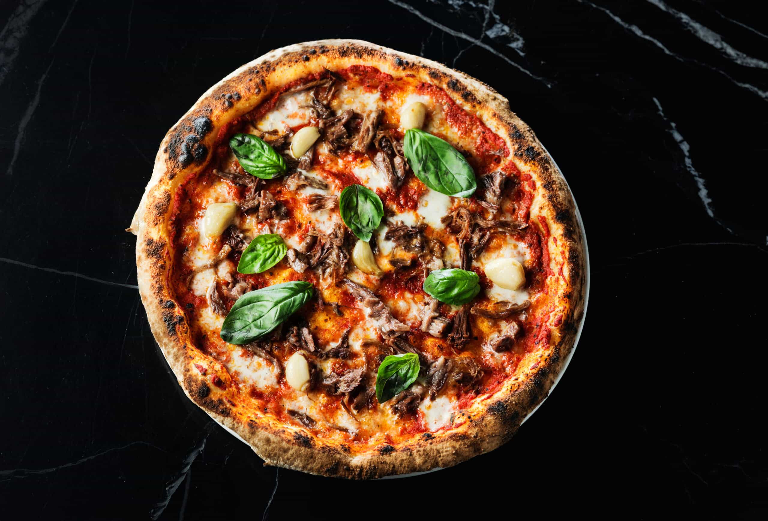 Stone-oven pizza with tomato, meat and basil