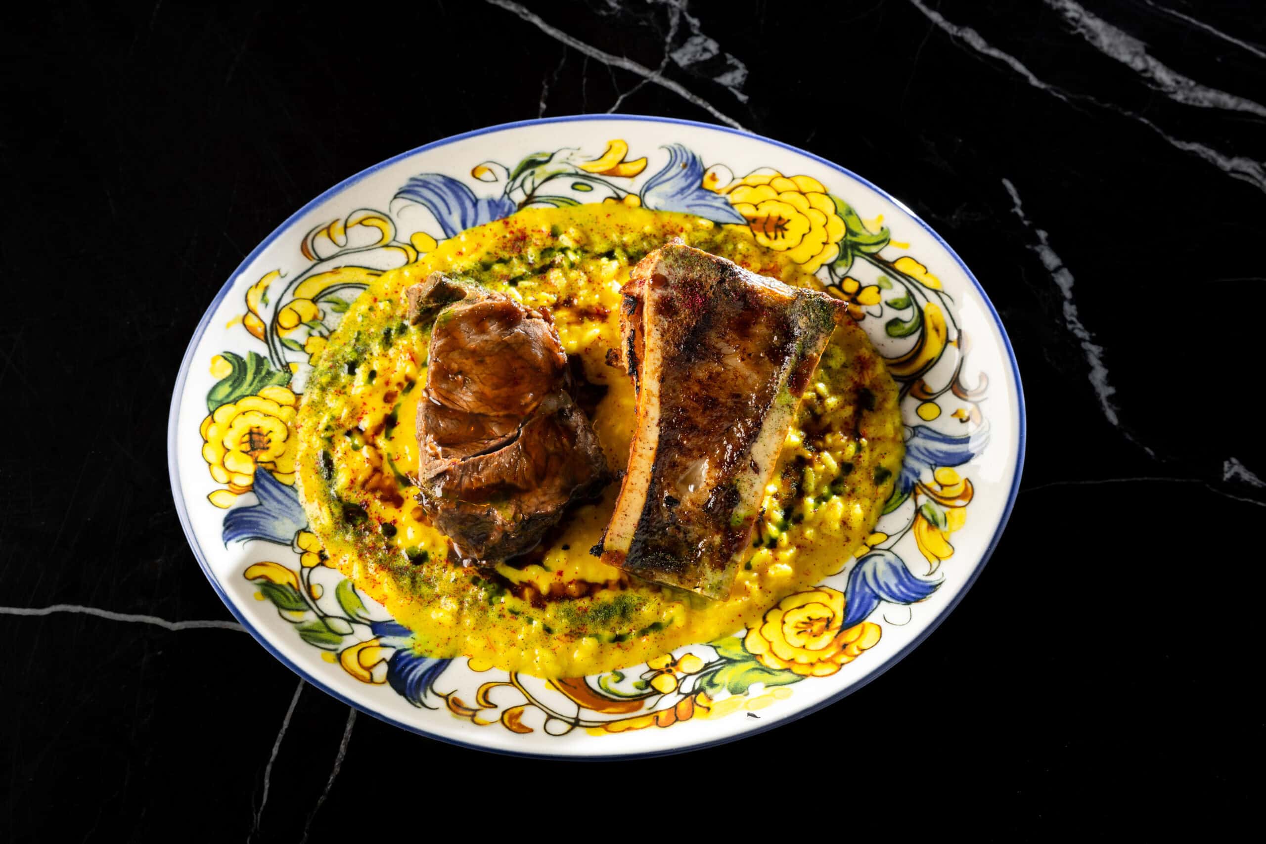 Meat dish on saffron risotto served on a painted plate