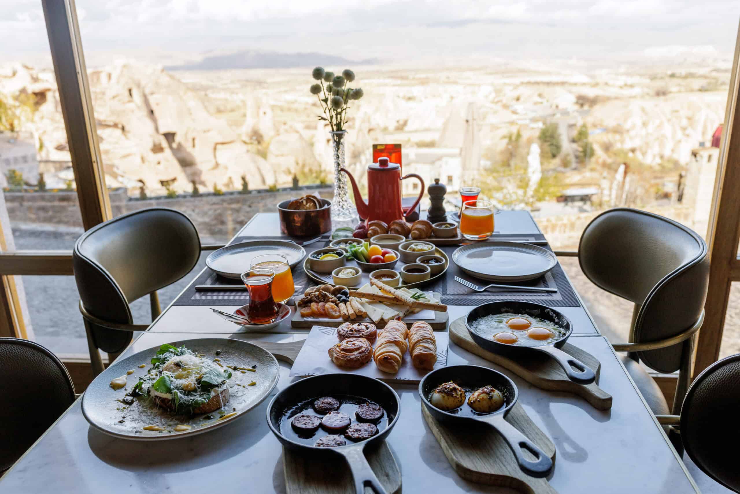 Shared table of dishes by a window overlooking Cappadocia