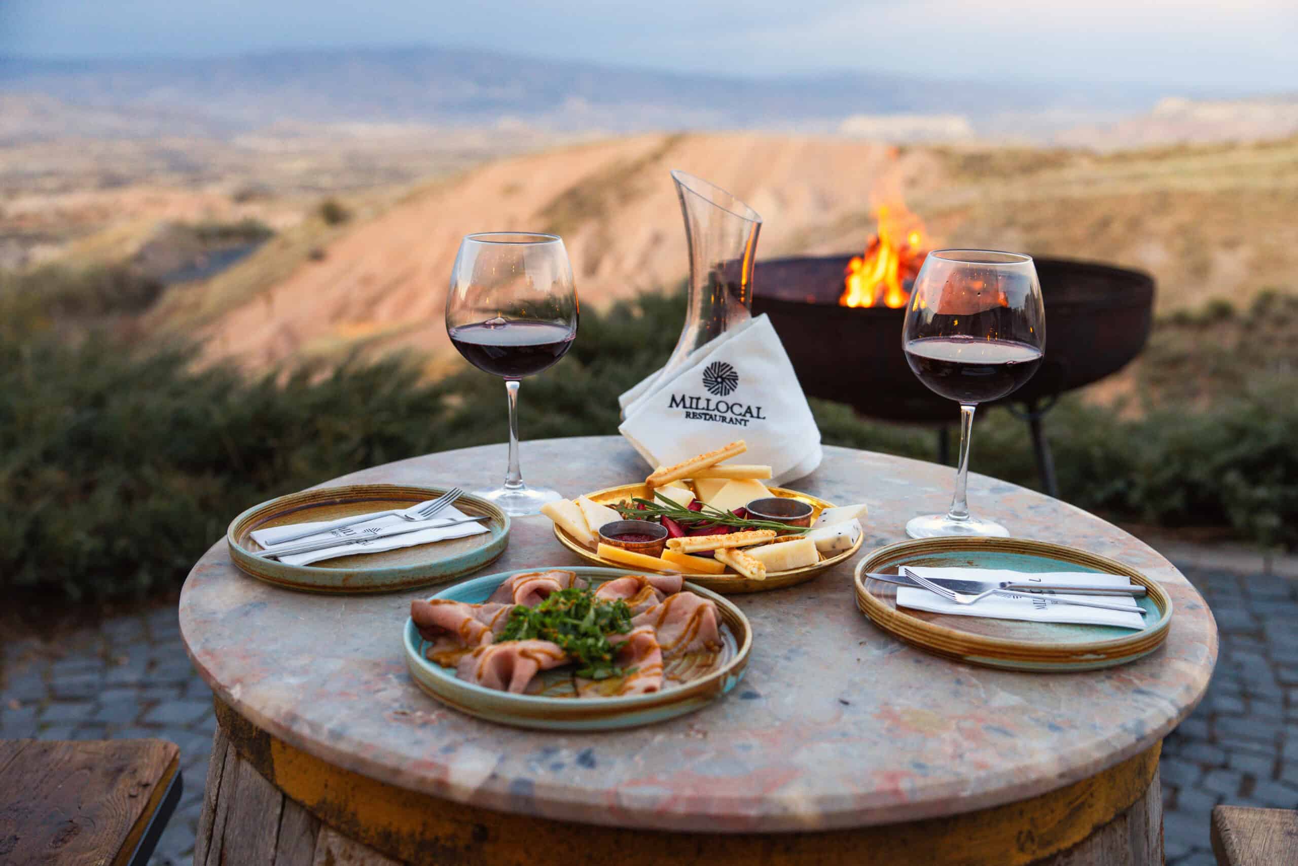 Wine glasses and meze on a terrace table with valley view