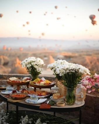 Sunrise breakfast table with flowers and hot air balloons in the sky