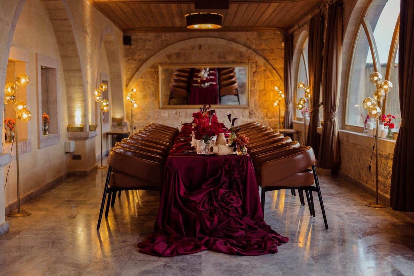 Banquet table with red linens in a stone hall