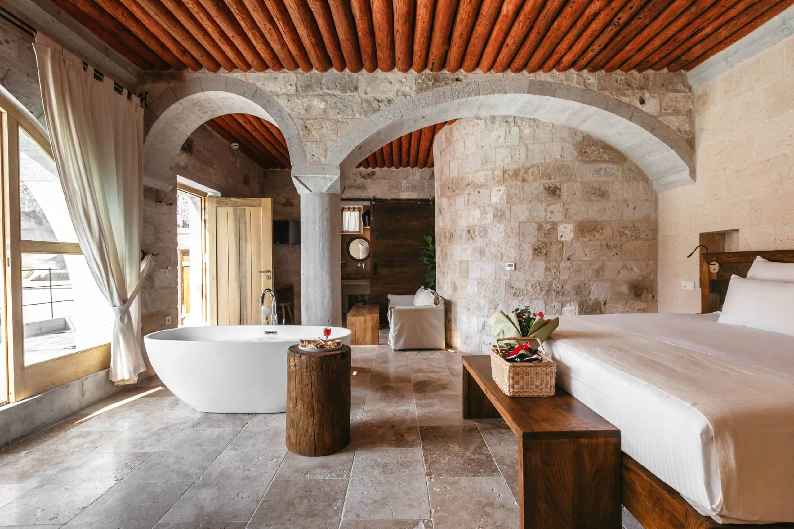 Pool Suite With View: freestanding bathtub, double bed and stone arches