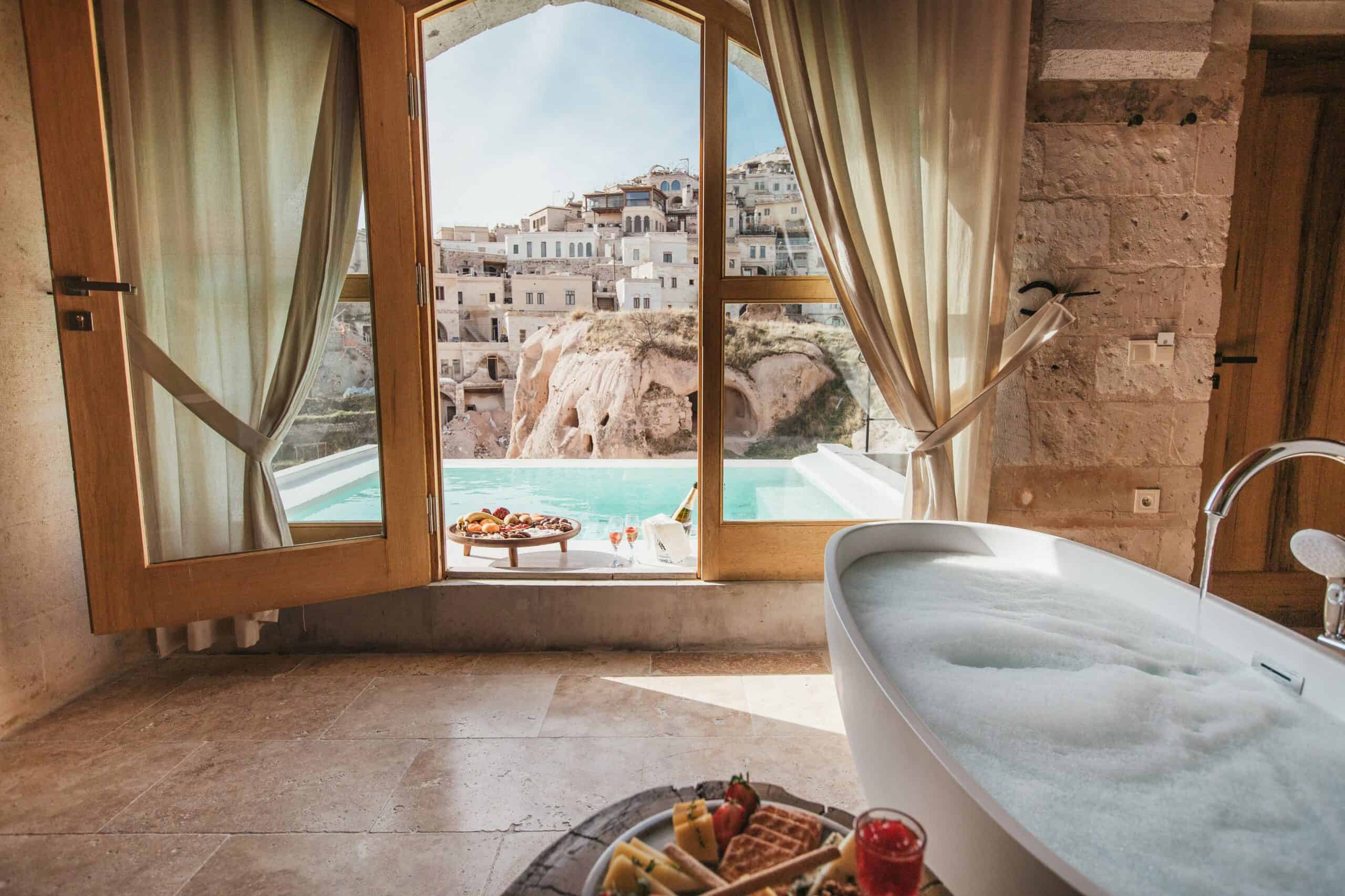 Pool Suite With View: bathtub and window overlooking the outdoor pool and Uçhisar