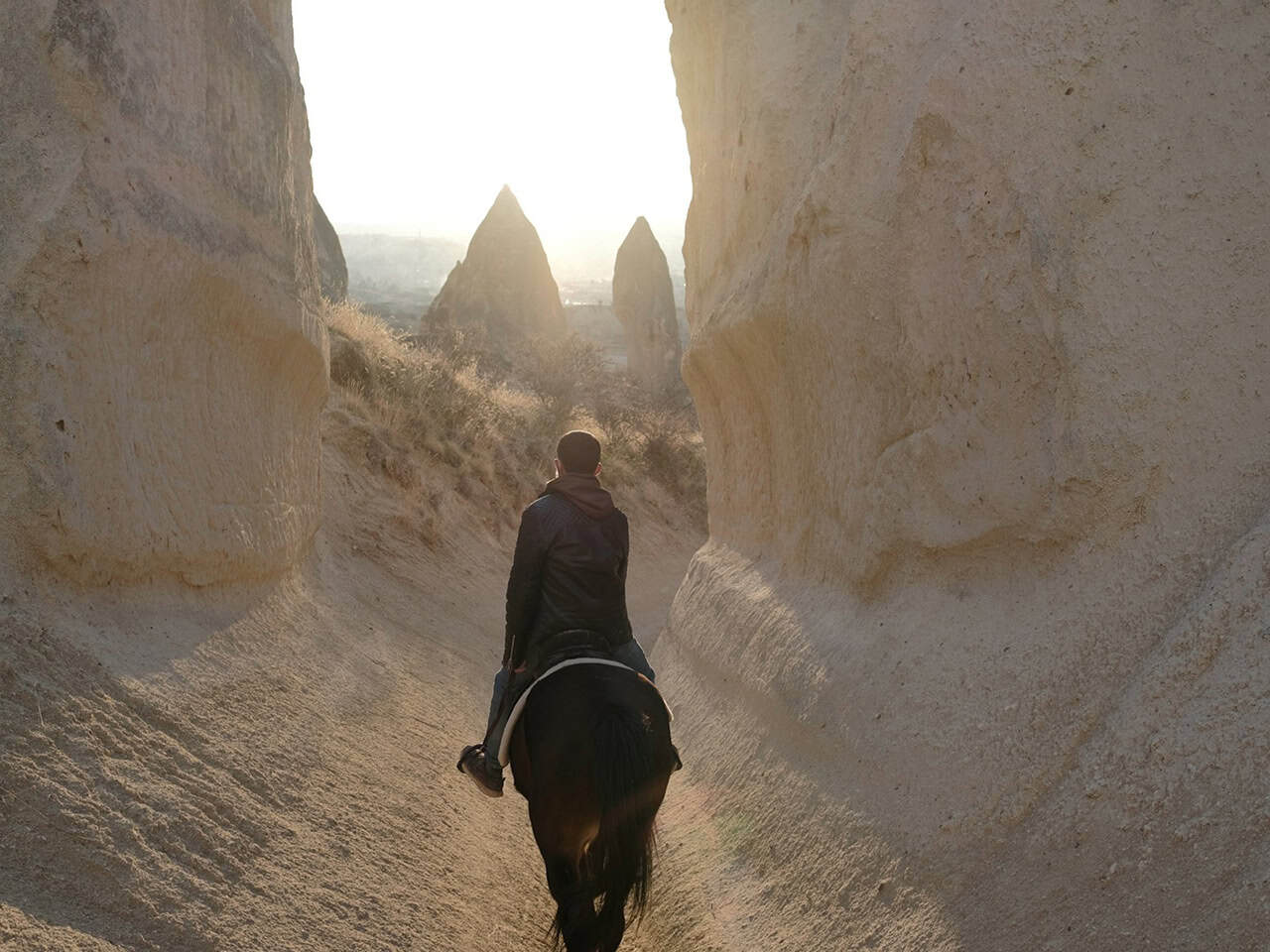 Horse rider in a narrow valley among the fairy chimneys of Cappadocia