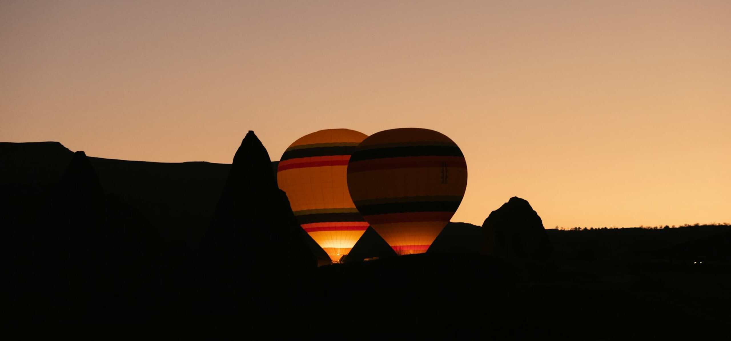 Silhouettes of hot air balloons at dusk over Cappadocia